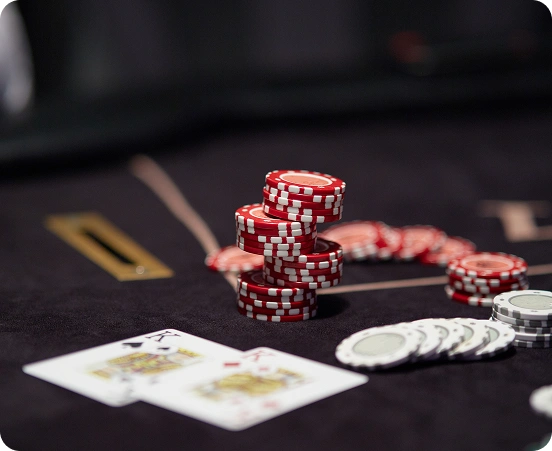 Pókersztár, rajta egymásra halmozott piros és fehér zsetonok, szétszórt zsetonok és két felfedett kártya, ami feszült, versenyszerű légkört teremt