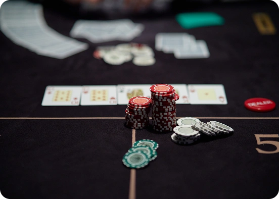 Pókersztár, rajta piros és zöld zsetonok halmaza, valamint nyerő kézben elrendezett kártyák. A légkör feszültséget és izgalmat sugároz