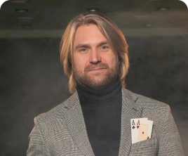 Kockás öltönyös férfi egy pohár whiskyt tart a kezében, zsebében két ász látható. Magabiztosan áll a homályosan megvilágított kaszinóban, és nyugodt, laza hangulatot áraszt